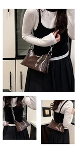 Detail of dark brown faux leather underarm bag with thick silver chain and round pendant