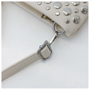 Close-up of cream white PU handbag with silver round rivets and metal shoulder strap buckle