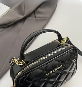 Détail du sac à main matelassé noir montrant la fermeture dorée et la poignée ronde