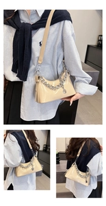 Detail of glossy beige patent leather underarm bag with bold silver chain and strap