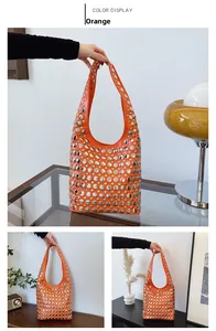 Détail d'un sac hobo orange orné de rivets argentés polis avec une bandoulière large