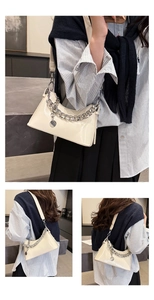 Detail view of cream oil-wax leather shoulder bag with chunky silver chain and round charm