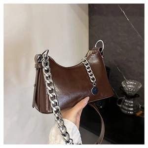 Detail of dark brown oil-wax leather baguette bag with silver chain and long strap