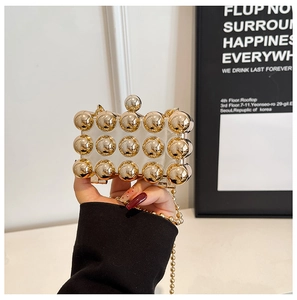Detail of mini party clutch bag with golden metallic beads and ball lock held by hand