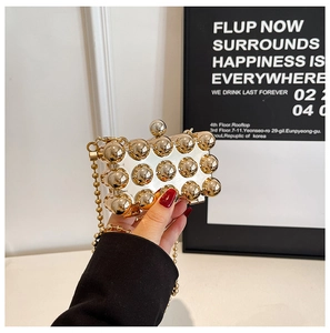 Detail of gold hard shell evening bag featuring 3D metal spheres and a beaded chain