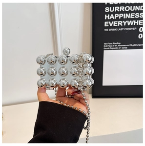 Detail of silver mirror mini party bag featuring decorative metal beads and ball chain strap
