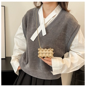 Close-up of golden mini evening bag with 3D spherical studs and a fine metal chain