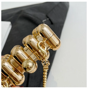 Macro shot of mini gold evening bag with modular cylinders and polished mirror finish