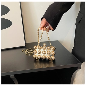 Detailed view of mini evening bag with gold spheres and round bead chain strap