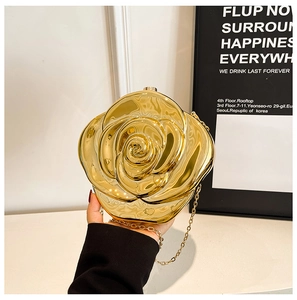 Detailed close-up of a 3D gold rose evening clutch bag with chain strap held in hand