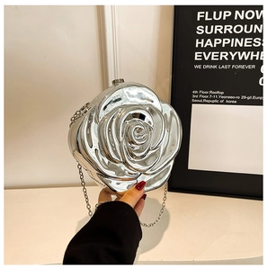 Detail of silver rose-shaped evening clutch bag with metallic petals and chain strap