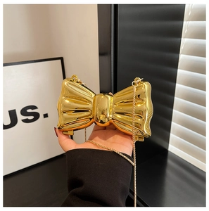 Detail of a mini golden bow-shaped hard shell clutch bag with a fine metal chain strap