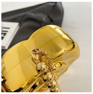 Detail of gold high-gloss hard shell evening bag with unique bead chain and metallic clasp