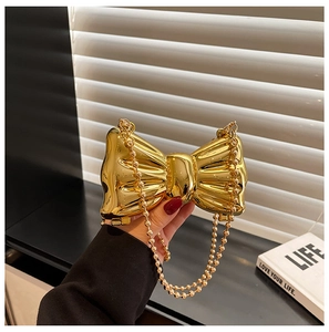 Mini golden bow-shaped evening bag with a metallic mirror finish and pearl chain strap