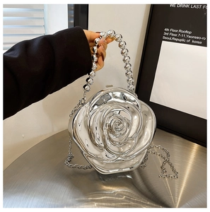Detail of silver rose flower clutch bag with mirror finish and bead handle