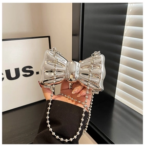Macro detail of silver mirror finish bow clutch bag with metallic ball chain strap