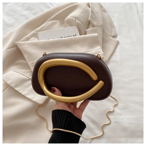 Detail of dark brown evening bag with golden C-shaped handle and metal snake chain