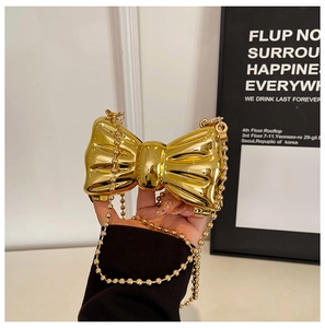 Close-up of golden bow-shaped evening clutch bag with glossy metallic mirror finish