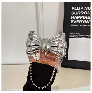 Close-up of metallic silver bow clutch bag with beaded chain and textured finish