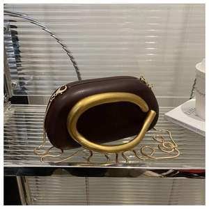 Macro shot of deep wine red leather evening bag with matte gold abstract handle