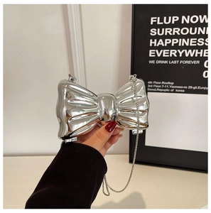 Close-up of a silver bow evening bag with a polished metallic finish and chain strap