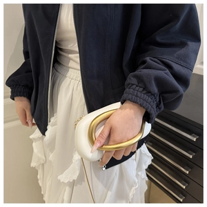 Detail of white leather handbag with oversized matte gold ring handle and snake chain