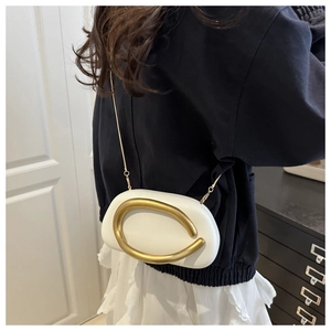 Close-up of a white leather bag with a gold metal ornament and chain strap worn by a woman
