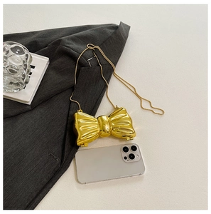 Close-up of golden bow-shaped metal mini bag with chain strap and size reference