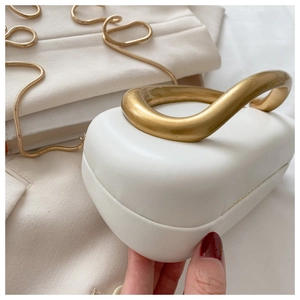 Close-up of white leather evening bag featuring a curved gold metal handle and luxury texture