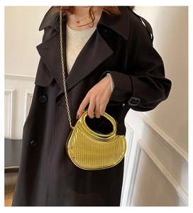 Detail of golden semi-circle handbag with vertical pleated texture and metal chain
