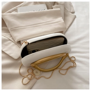 Detailed interior of a white crossbody evening bag with gold handle and chain strap