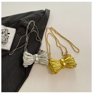 Close-up of gold and silver mini bow-shaped evening bags with metal bead chain straps