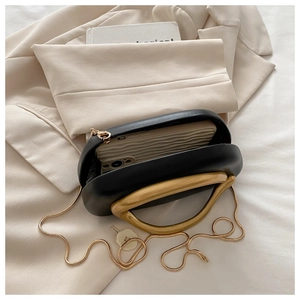 Detailed view of black matte leather evening bag with large gold handle and snake chain strap