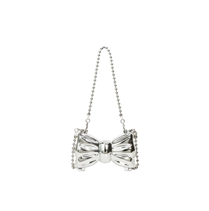 Detail of creative bow-shaped evening clutch in polished silver metallic finish with chain