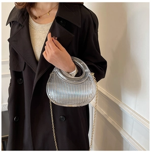 Close-up of semi-circle transparent pleated PVC bag with a gold metal chain strap
