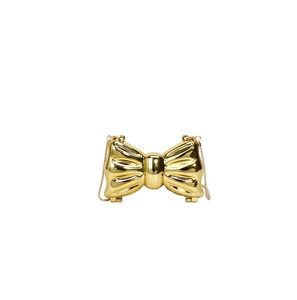 Macro detail of gold bow-shaped evening clutch with glossy mirror finish and metal chain