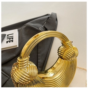 Makroansicht der goldenen Abendtasche mit vertikaler Textur und elegantem Knotengriff