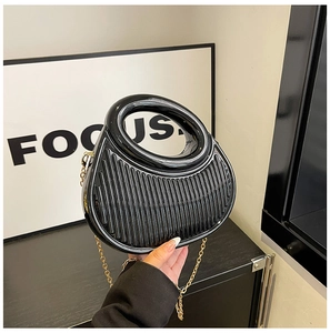 Detail of glossy black semi-circular handbag with vertical pleated texture and gold chain