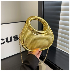 Close-up of golden metallic handbag featuring vertical pleats and oval cutout handle