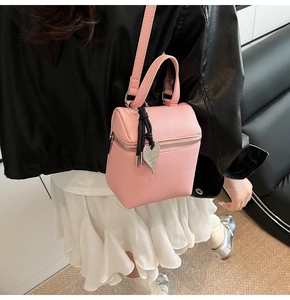 Dettaglio borsa a mano rosa in pelle con ciondolo a cuore e tracolla regolabile