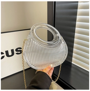 Detailed view of clear acrylic clutch bag with pleated texture and gold chain strap