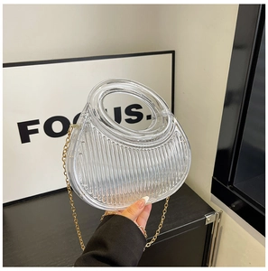 Detailed view of clear acrylic evening clutch with vertical ridges and gold metal chain