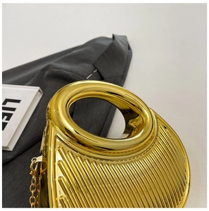 Close-up of golden ring handle and vertical pleated texture on an evening clutch bag