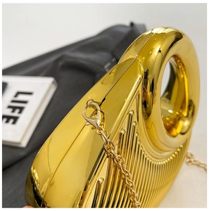 Close-up of gold evening clutch featuring sleek vertical stripes and circular handle
