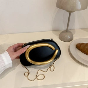 Elegant black oval evening bag with gold C-handle and snakeskin chain strap