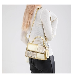 Vue arrière du sac bandoulière doré avec texture serpent sur un mannequin en pull blanc
