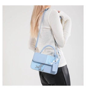 Détail du sac bandoulière bleu clair avec mélange de textures et motif serpent
