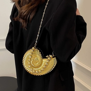Close-up of golden shell evening bag with beaded spiral texture and chain strap