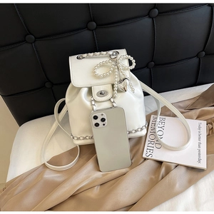 Close-up of white patent leather backpack with pearl bow and silver heart charms