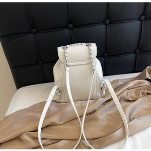 Close-up of white glossy patent leather backpack with silver chain and leather straps